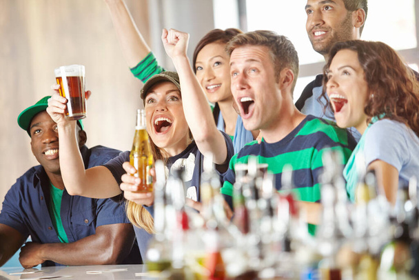 スポーツは人々を結びつける。バーでお気に入りのチームを応援している興奮した友人のグループ - 写真・画像