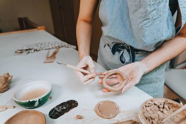 Крупним планом жіночі руки працюють з глиною, роблячи чашку в майстерні. Вибірковий фокус
. - Фото, зображення
