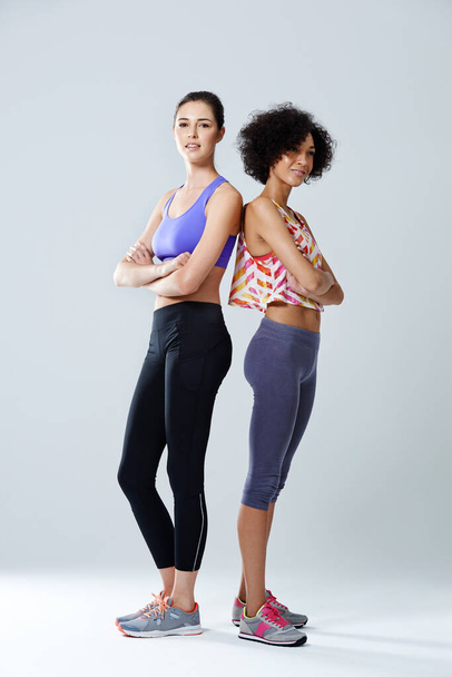 Sneaker vor Stelletos. zwei Frauen in Sportkleidung im Studio - Foto, Bild