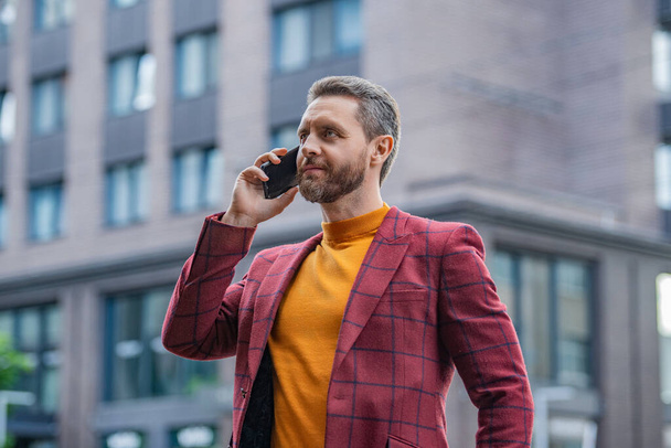 businessman has cellphone call in the street. businessman call on cellphone outside. photo of businessman call on cellphone and talk. businessman has cellphone call outdoor. - Foto, imagen