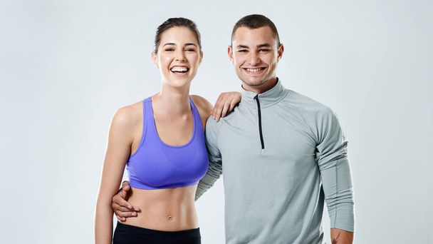 He makes working out seem like fun. Portrait of a sporty young couple standing against a gray background - 写真・画像