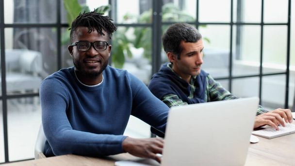 アフリカ系白人の同僚はPC企業のアプリを使いメンターは新しい従業員にインターンシップやチームワークの概念を教え - 写真・画像