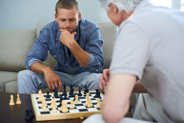 Egy mozdulat megváltoztathatja a játék menetét. apa és fia együtt sakkoznak otthon. - Fotó, kép