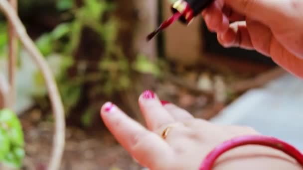 νεαρή κοπέλα κάνει βερνίκι νυχιών στα νύχια την ημέρα σε λεπτομέρειες - Πλάνα, βίντεο