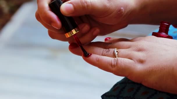 νεαρή κοπέλα κάνει βερνίκι νυχιών στα νύχια την ημέρα σε λεπτομέρειες - Πλάνα, βίντεο