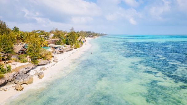 L'isola di Zanzibar ospita una splendida spiaggia tropicale che vi toglierà sicuramente il fiato. La sabbia bianca, le palme e le acque turchesi cristalline si fondono perfettamente con il cielo blu con morbide nuvole in una calda giornata estiva.,  - Foto, immagini