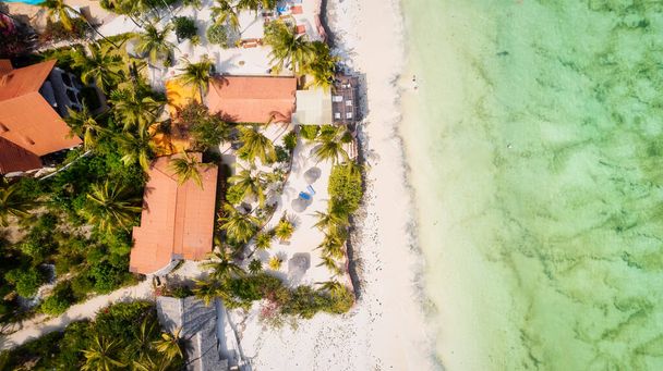 Flucht in ein tropisches Paradies mit einem Strand wie aus dem Bilderbuch mit weißem Sand, schwankenden Palmen und kristallklarem türkisfarbenem Wasser vor blauem Himmel mit flauschigen Wolken an einem sonnigen Sommertag. Sansibar Island ist die ultimative  - Foto, Bild