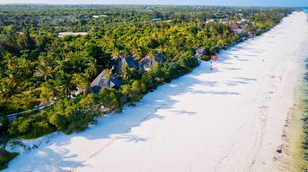 Útěk do tropického ráje s obrázkově dokonalou pláží s bílým pískem, kymácejícími se palmami a křišťálově čistou tyrkysovou vodou proti modré obloze s nadýchanými mraky za slunečného letního dne. Ostrov Zanzibar je největší  - Fotografie, Obrázek