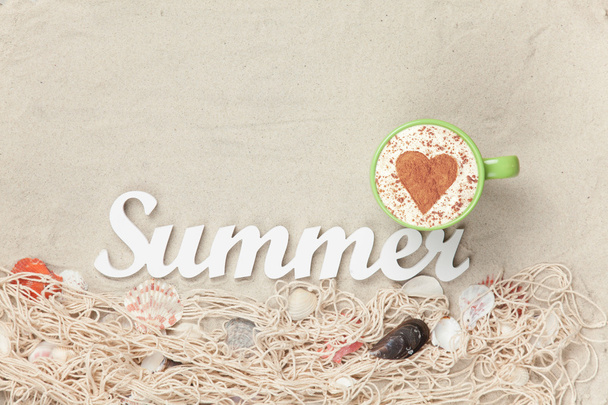 Κύπελλο, λέξη καλοκαίρι και δίχτυ με κοχύλια στην άμμο - Φωτογραφία, εικόνα