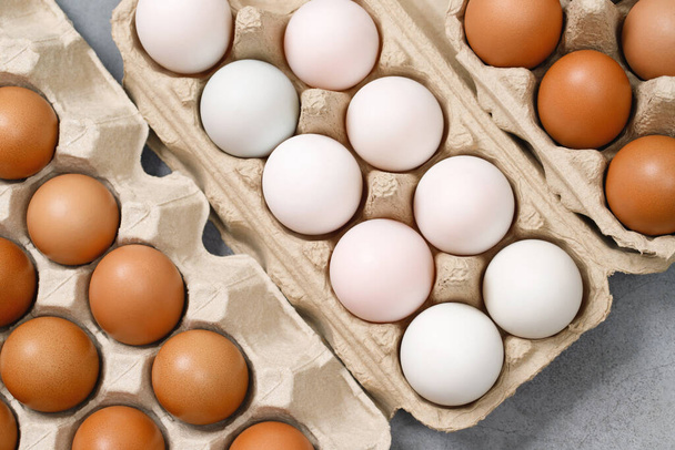 Fehér kacsa tojás és csirke tojás egy kartondobozban készen áll a főzésre. az asztalon a konyhában - Fotó, kép