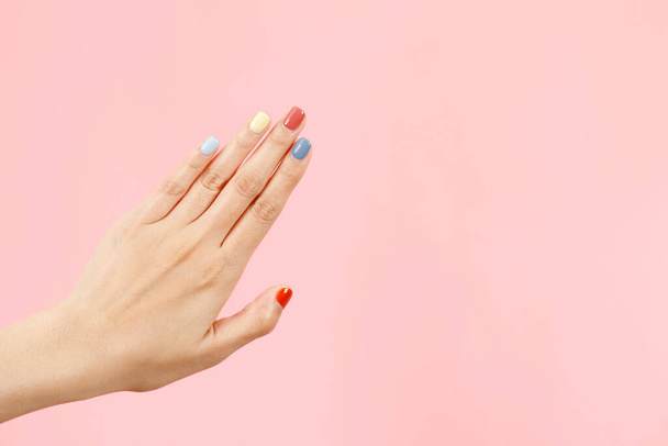 Mooie vrouwelijke hand schilderen acryl gel nagels. Modestijl. Roze achtergrond. - Foto, afbeelding
