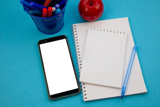 Mobile phone mockup blue background top view. Workplace copy space. Notepad, pen. Study and work planning. Self-learning. Online business course. Education remotely. Flatlay of blank screen cellphone - Φωτογραφία, εικόνα