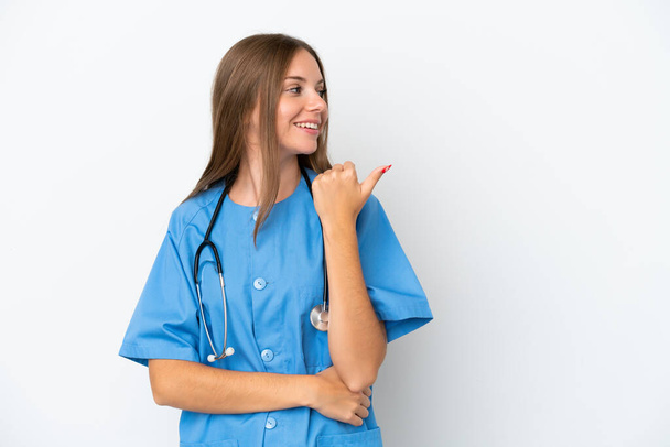 Jonge chirurg arts Litouwse vrouw geïsoleerd op witte achtergrond wijzend naar de zijkant om een product te presenteren - Foto, afbeelding