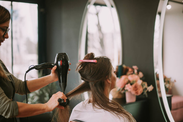 Fryzjer stojący i suszenie włosów jej klientów w salonie fryzjerskim - Zdjęcie, obraz