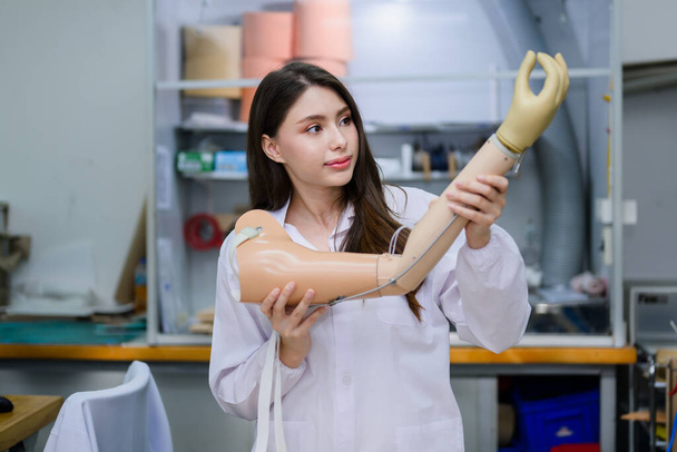 Protez kol kontrolü ve kontrol kalitesini elinde tutan genç protez teknisyen, laboratuarda çalışıyor, protez imalatında yüksek teknoloji uzmanı, yeni yapay - Fotoğraf, Görsel