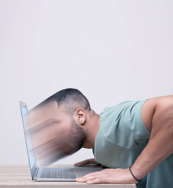Internet addiction. Young man dissolving in laptop at table - 写真・画像