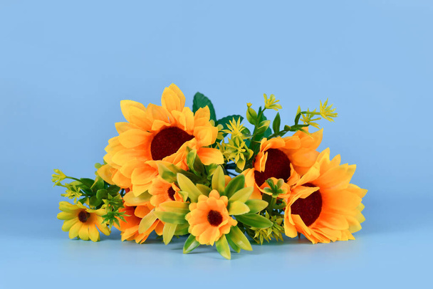 Bouquet of fake sunflowers on blue background - Foto, imagen