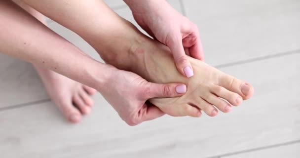 Kobieta robi masaż stóp rękami w domu zbliżenie 4k film slow motion. Problemy ze stawami stóp podczas noszenia butów z koncepcją obcasów - Materiał filmowy, wideo