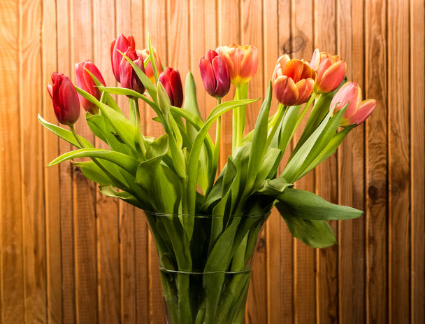 ouquet of tulips in a vase on a background of wooden boards - Zdjęcie, obraz