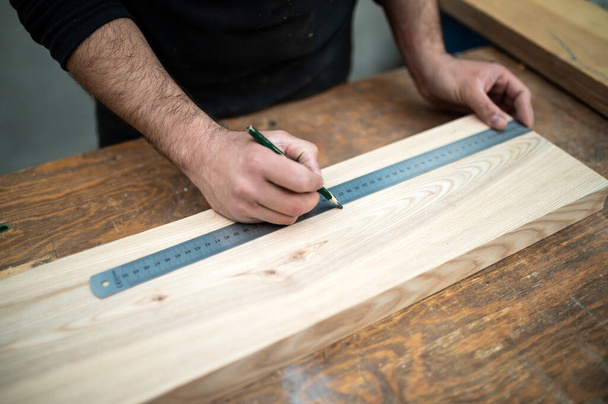 Carpintero midiendo una tabla de madera en el banco de trabajo - Foto, Imagen