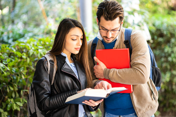 Two students, male and female, talking outdoors holding books - Foto, Bild