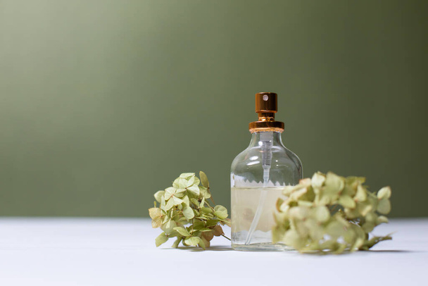 glass perfume bottles with sprigs of hydrangea on a light background - Фото, зображення