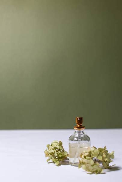 glass perfume bottles with sprigs of hydrangea on a light background - Fotó, kép