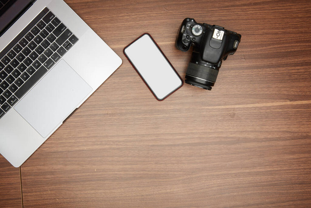 Egy laptop és egy kamera egy fából készült asztalon. - Fotó, kép