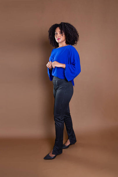 Confident and happy young businesswoman standing against marron background. Studio portrait. - Фото, изображение