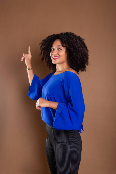 Beautiful young business woman making hand gestures. Standing against a brown background. Studio portrait. - Foto, Imagem