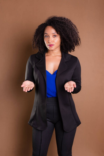Woman dressed in black blazer standing against brown background. Business woman. Studio portrait. - Photo, Image