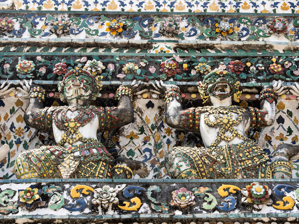 Diese prachtvollen, kunstvollen Statuen schmücken die Fassade des Wat Arun und fallen durch ihre lebhaften Farben und aufwendigen Designs auf. Als Hüter des Tempels symbolisieren sie Stärke und Schutz, während ihre anmutigen Körperhaltungen und heiteren Gesichtsausdrücke - Foto, Bild