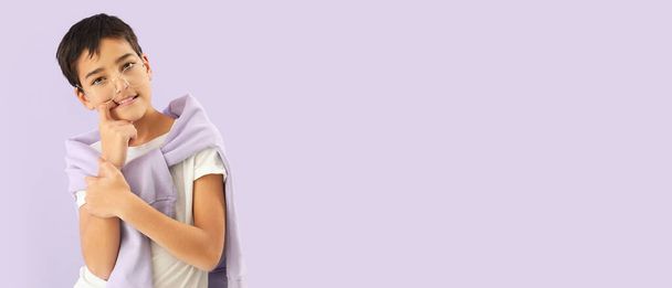 Mały chłopiec obgryzający paznokcie na liliowym tle z miejscem na tekst - Zdjęcie, obraz