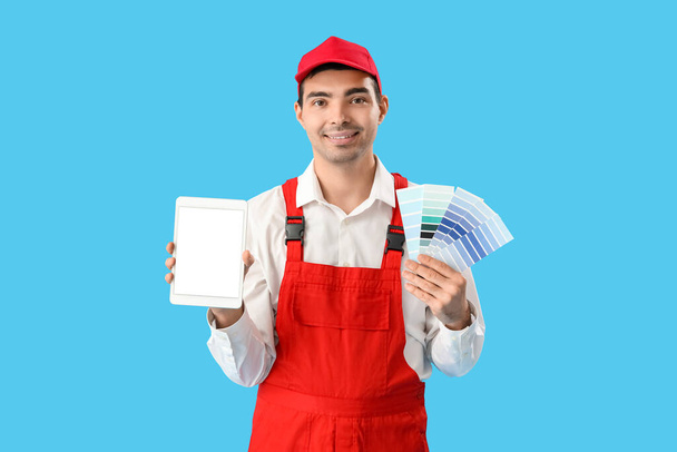 Male painter with color palettes and tablet computer on blue background - Foto, Bild
