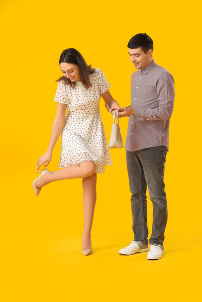 Joven sosteniendo la mano de su novia sobre fondo amarillo - Foto, Imagen