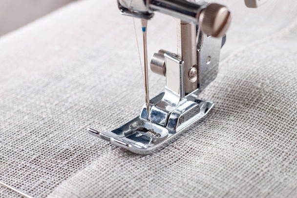 Máquina de coser moderna prensatelas con tela de lino e hilo, primer plano. Costura proceso ropa, cortinas, tapicería. Negocio, hobby, hecho a mano, cero residuos, reciclaje, concepto de reparación - Foto, Imagen