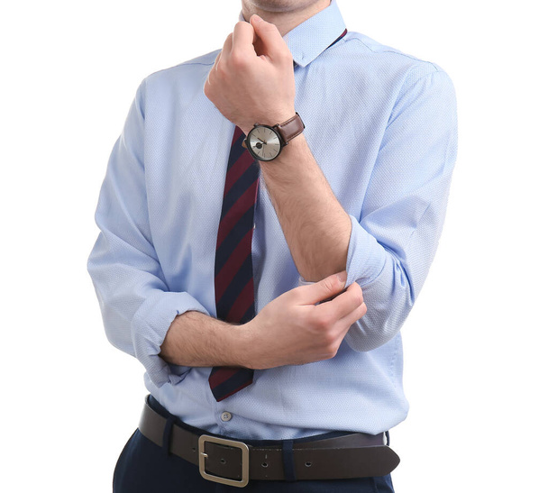 Young businessman rolling up his sleeve on white background - Photo, Image