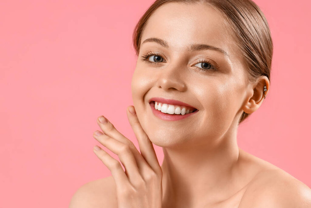 Csinos fiatal nő egészséges bőr rózsaszín háttér - Fotó, kép