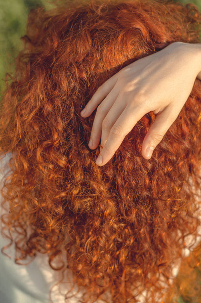 Vrouwelijke hand streelt mooi rood krullend haar, close-up - Foto, afbeelding