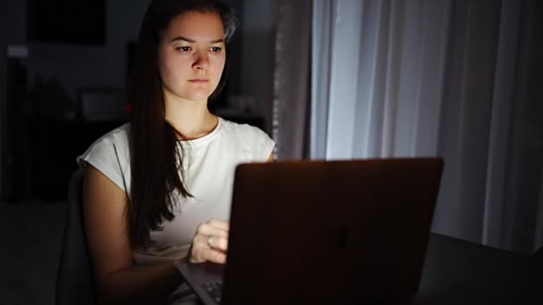Casual beautiful woman working on a laptop at the night at home. High quality FullHD footage - Záběry, video