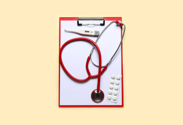 Stethoscope, clipboard, thermometer and pills on beige background - Foto, Imagem