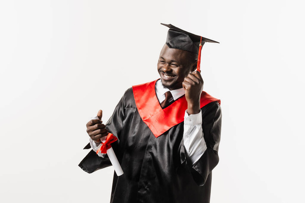 Graduierung. Glücklicher afrikanischer Mann mit einem Lächeln und einem Diplom mit Ehren in der Hand auf weißem Hintergrund. Afrikanischer Hochschulabsolvent schloss sein Studium ab und erwarb einen Master-Abschluss - Foto, Bild