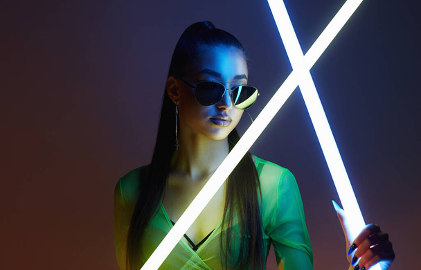 beautiful woman with neon lamp. Dancer girl in sunglasses in color lights. - Photo, Image