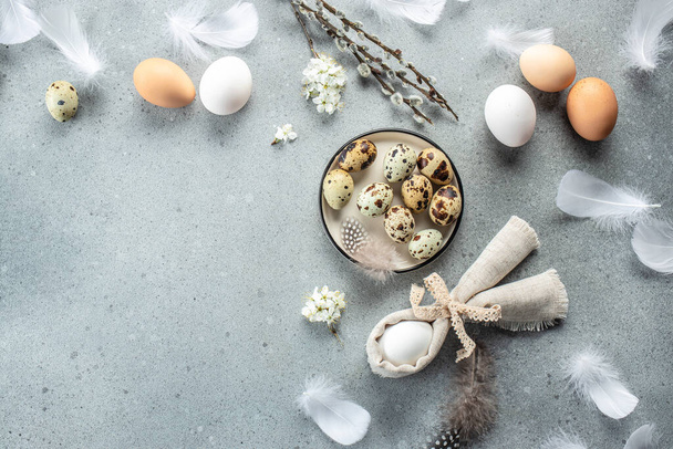 Feestelijke paastafel met eieren en bloemdecoratie op lichtgrijze achtergrond. Gelukkig Pasen vakantie concept. plaats voor tekst, bovenaanzicht. - Foto, afbeelding