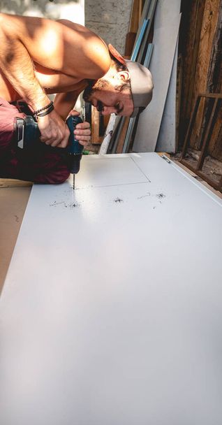 Ajuste y centrado: trabajador latino sin agujeros de perforación de camisa en tablero de acero por la tarde (con gran espacio de copia) - Foto, imagen