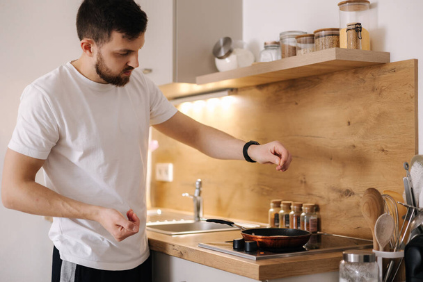 Красивий чоловік готує їжу вдома. Молодий чоловік дивує свою кохану жінку і готує сніданок на кухні. Високоякісна фотографія
 - Фото, зображення