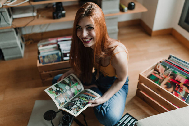 Красивая молодая женщина улыбается в камеру, когда читает комиксы. Высокое качество фото - Фото, изображение