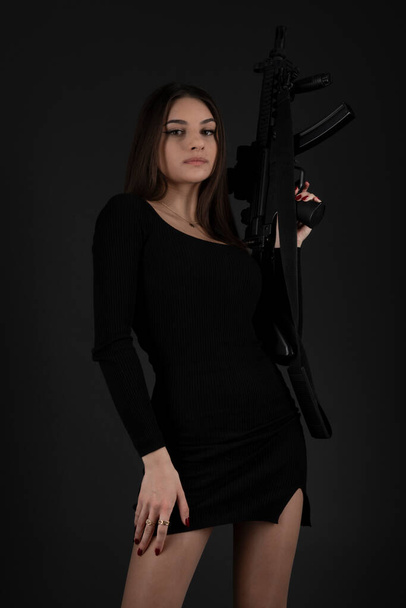 Beautiful brunette woman with a gun in her hand - Foto, imagen
