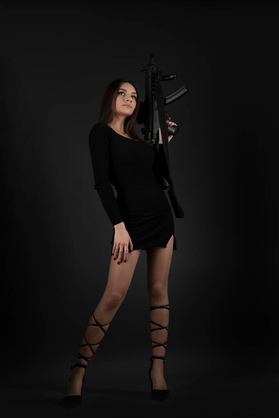Beautiful brunette woman with a gun in her hand - Фото, изображение