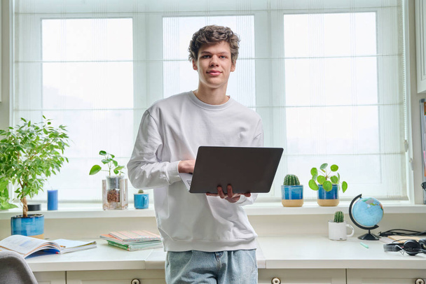 Portrait of friendly young college student guy with laptop at home. Handsome male 18-20 years old looking at camera. Online internet technologies, remote e-learning, study, leisure, communication - Foto, Imagem